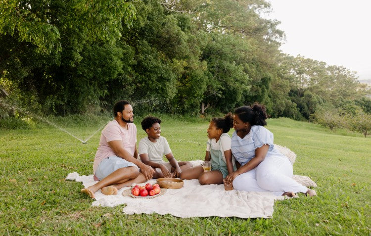 family sitting on lawn having picnic with 9 pattern sprinkler in the background