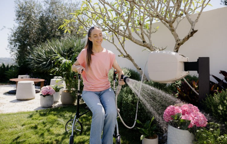 woman sitting in walker watering flowers using Evolve™ Retractable Hose Reel