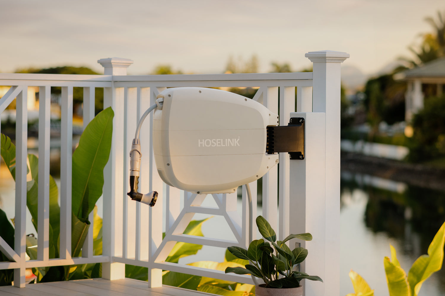 Beige Evolve Retractable Hose Reel mounted on a white timber post of a deck, overlooking a river