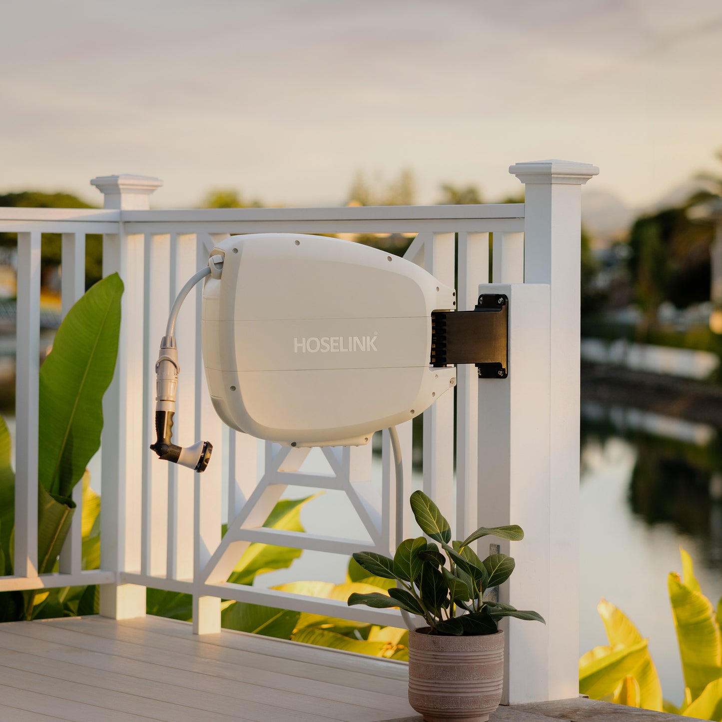 Evolve Beige Retractable hose Reel mounted on a white fence post overlooking a waterway in the background 