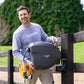 Ben Hayman installing a charcoal classic hose reel on a black wooden post next to a gravel road