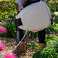 beige evolve retractable hose reel being mounted on an evolve mounting post is a mulch covered garden with green plants