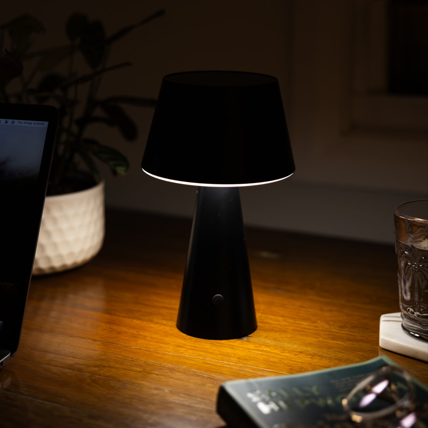 black table lantern on a desk next to a laptop and book