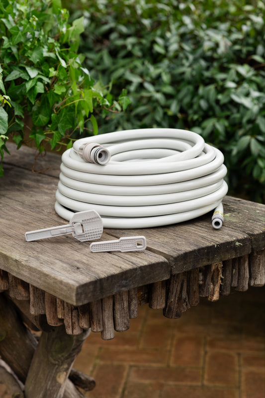 beige replacement 20m hose  and two safety keys sitting on a wooden table surrounded by green foliage 