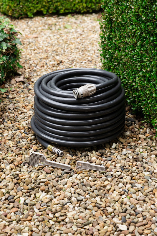 30m charcoal replacement hose for evolve hose reel and two safety keys on a brown gravel path surrounded by green hedges