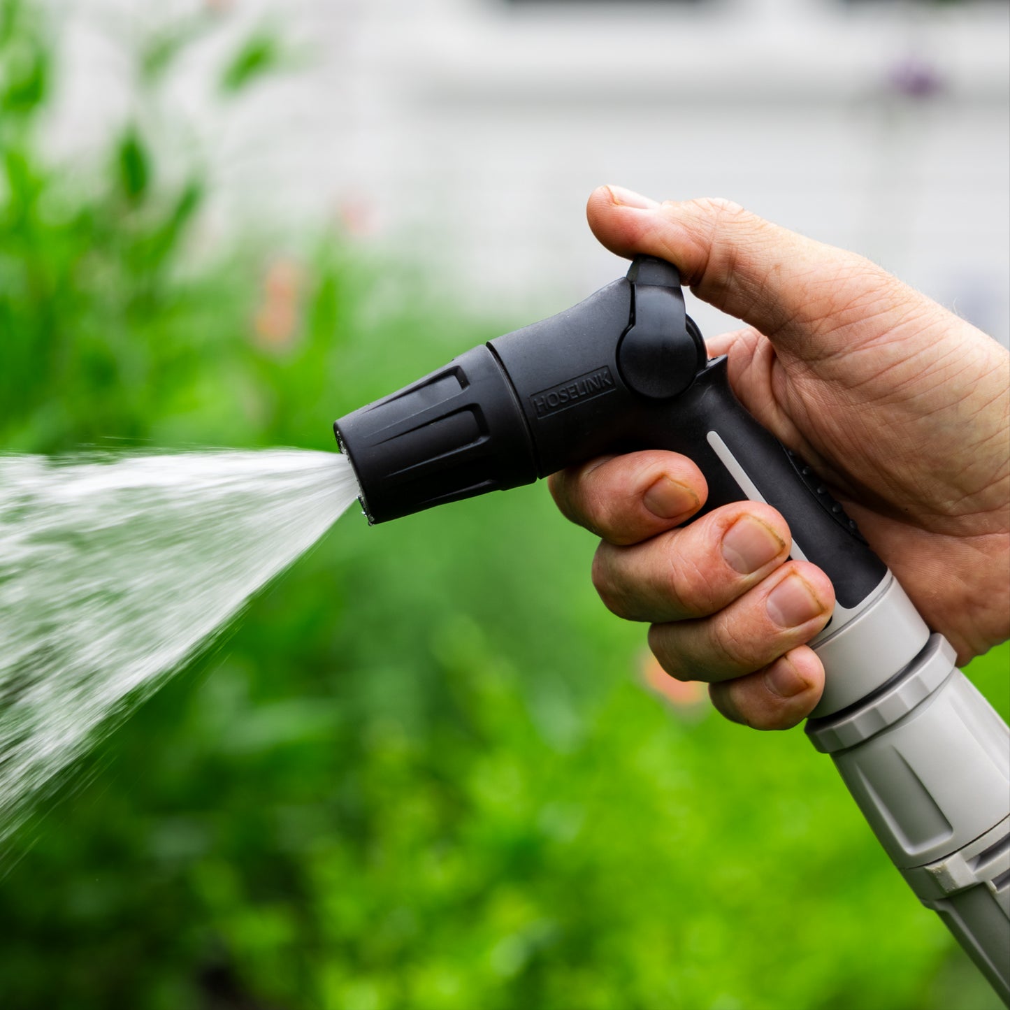 close up of com[act flow control nozzle watering a green bush with a cone shaped spray