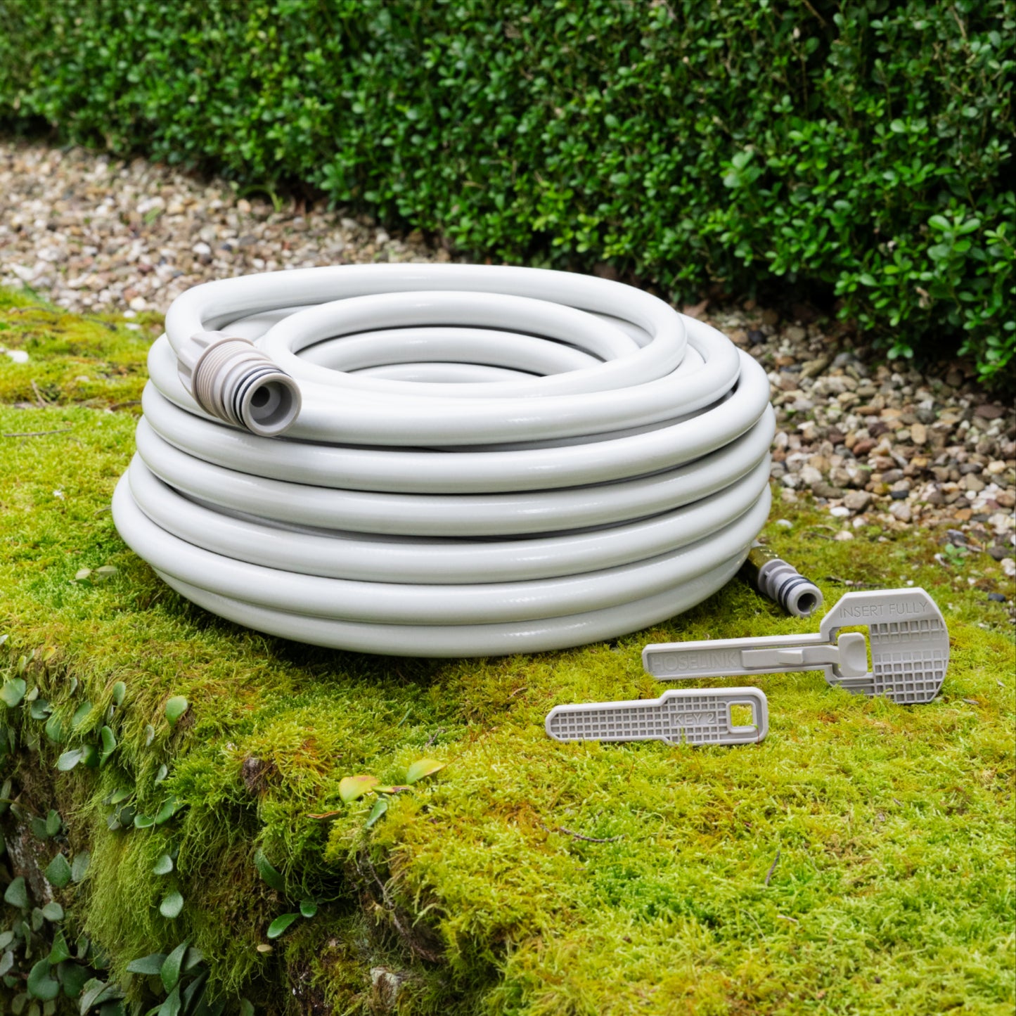 beige replacement 20m hose and two safety keys resting on a green moss covered retaining wall 