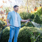 Ben Hayman in jeans and a blue shirt watering hedges with the compact flow control spray nozzle