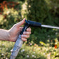 close up of a persons thumb operating the flow control lever of the compact spray nozzle spraying a jet style spray