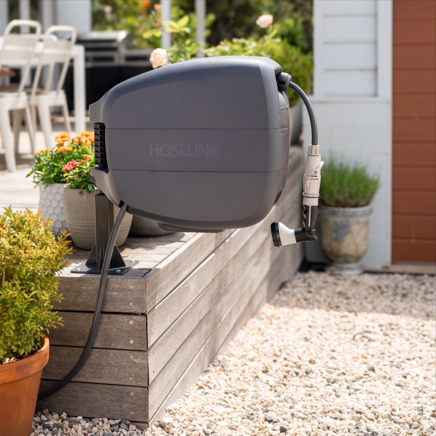 Evolve ground mount installed on the corner of a timber deck, with a charcoal evolve retractable hose reel installed on the mount