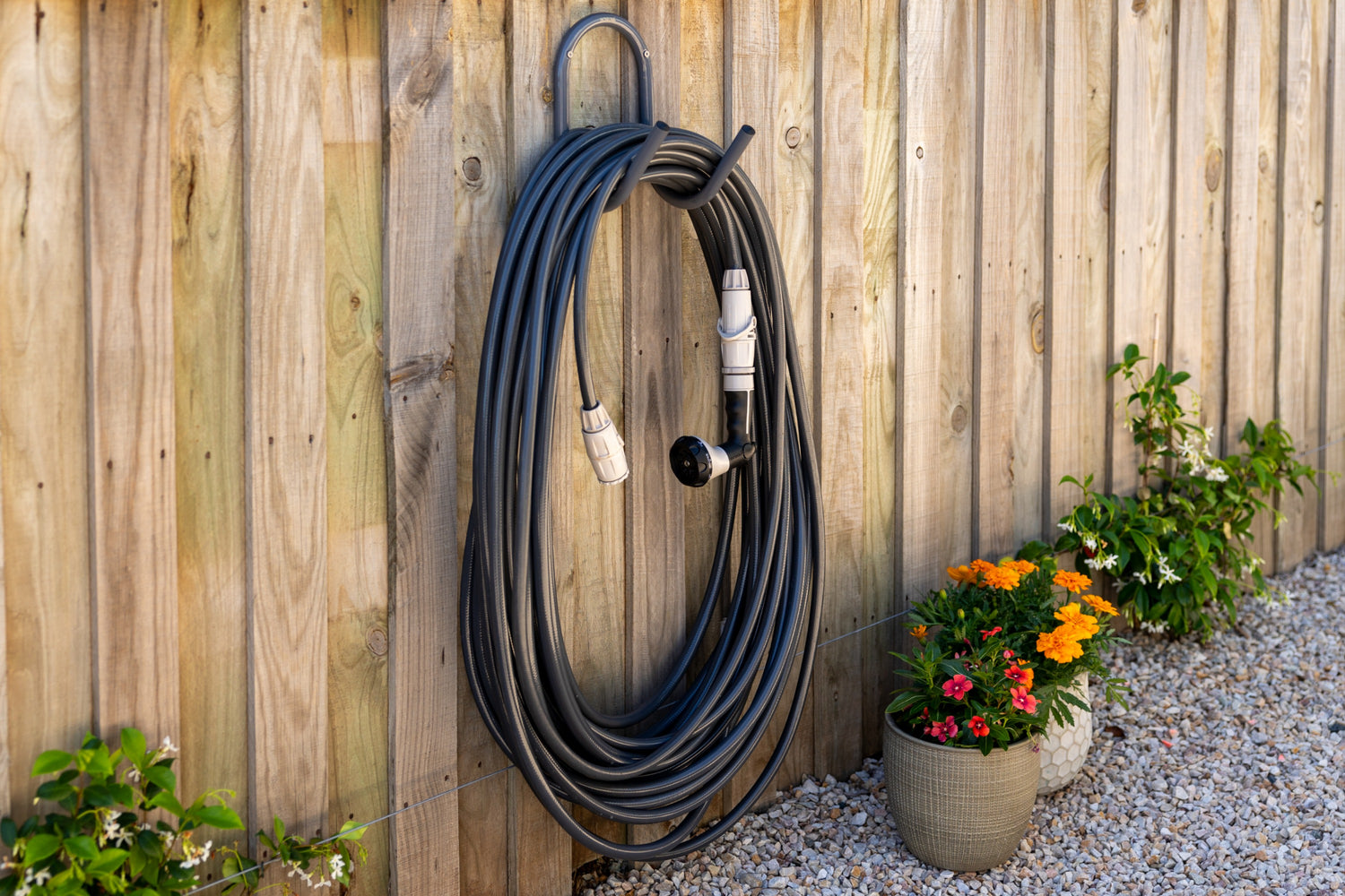 Charcoal hose and hanger mounted to a light brown timber fence