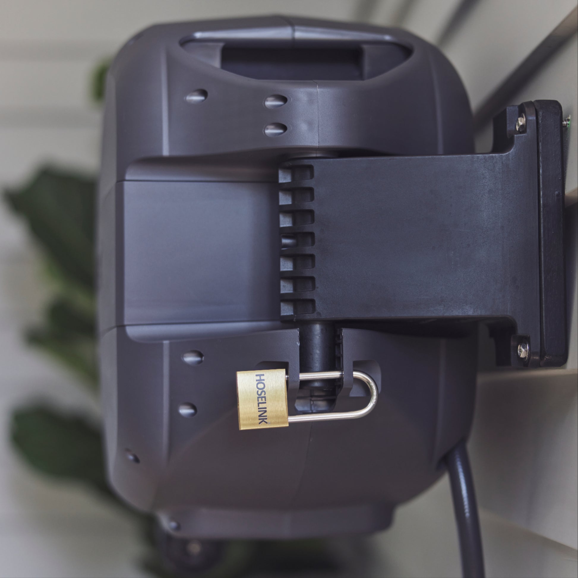 Back of the Charcoal Evolve Retractable Hose Reel mounted on weatherboard and secured on the bracket with an Evolve Padlock